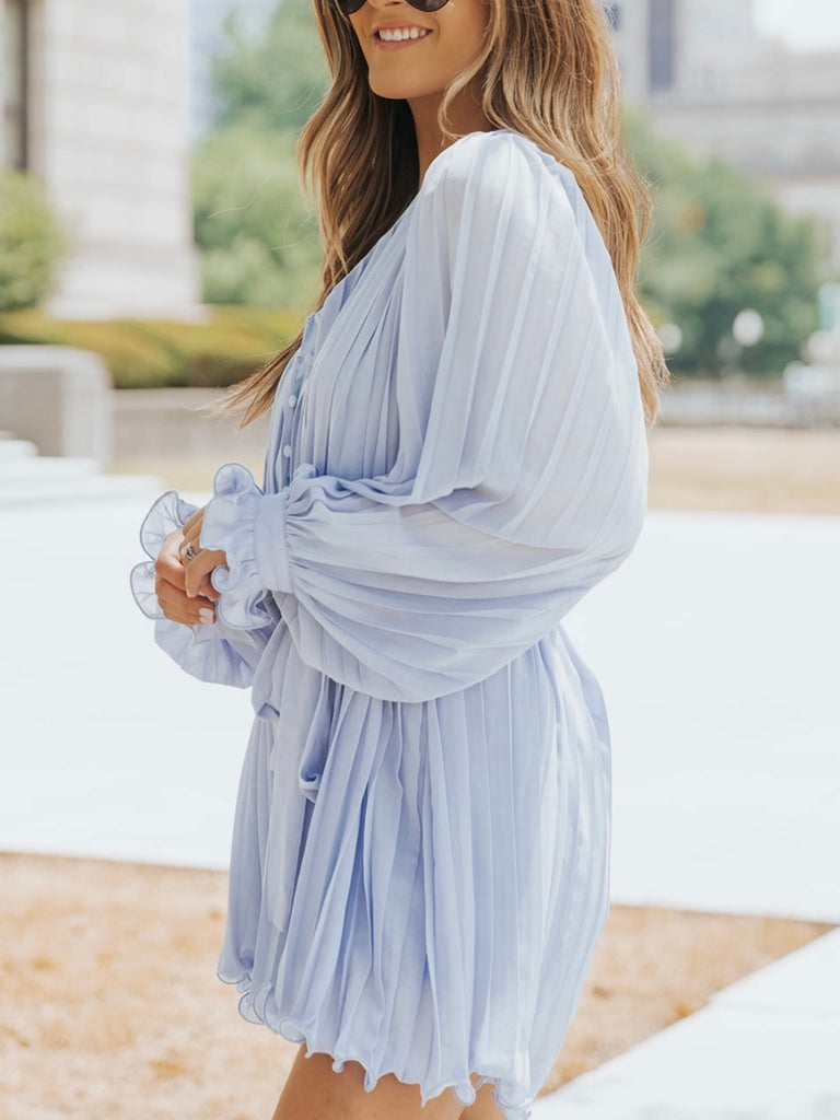 Playful V-neck Blue Pleated Romper Dress features a tie waist with a buttoned front, and frilly sleeves.