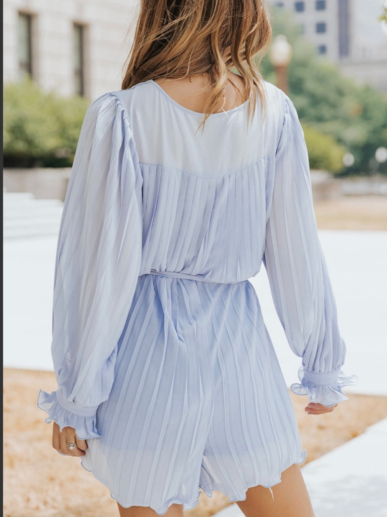 Playful V-neck Blue Pleated Romper Dress features a tie waist with a buttoned front.