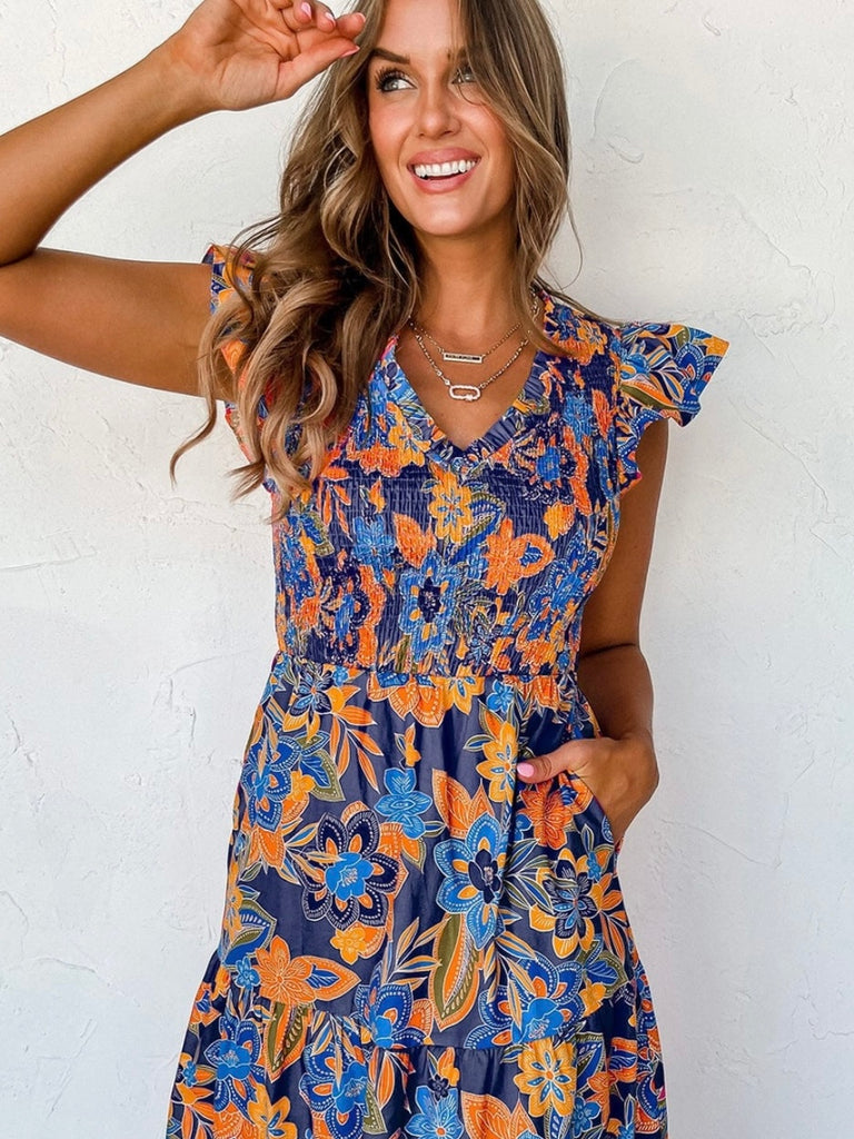 Boho Dress in shades of blue with pops of orange , and features a gorgeous floral print, smocked bodice, and tiered A-line silhouette.