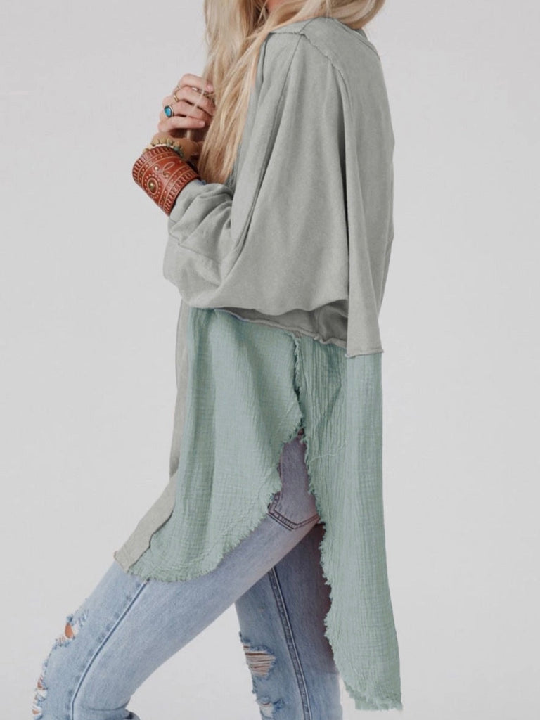 Grey Colour high-low tunic length and split hem pullover, features a round neckline and long sleeves, blend of crinkled gauze and knit, and raw edge design.