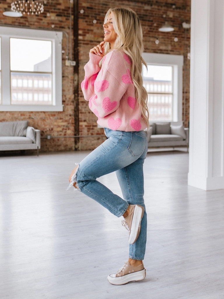 Pink sweater with contrasting fuzzy pink hearts, long sleeved.