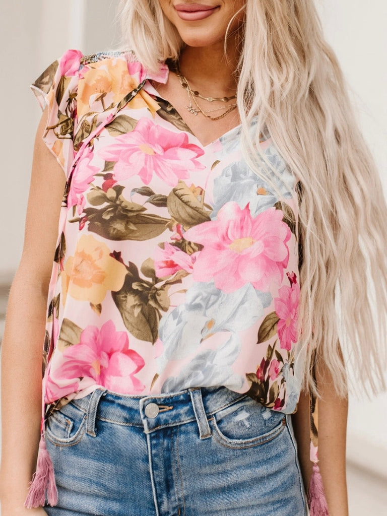 Floral Blouse Blouse features a delicate and feminine floral print, ruffled neckline, and tasseled tie neckline. 