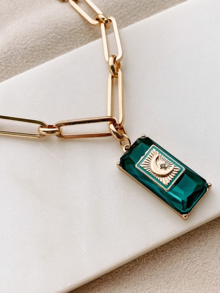 14.5" Gold Necklace, has a moon and star charm, and emerald gem detail with adjustable length and rectangular cable chain.