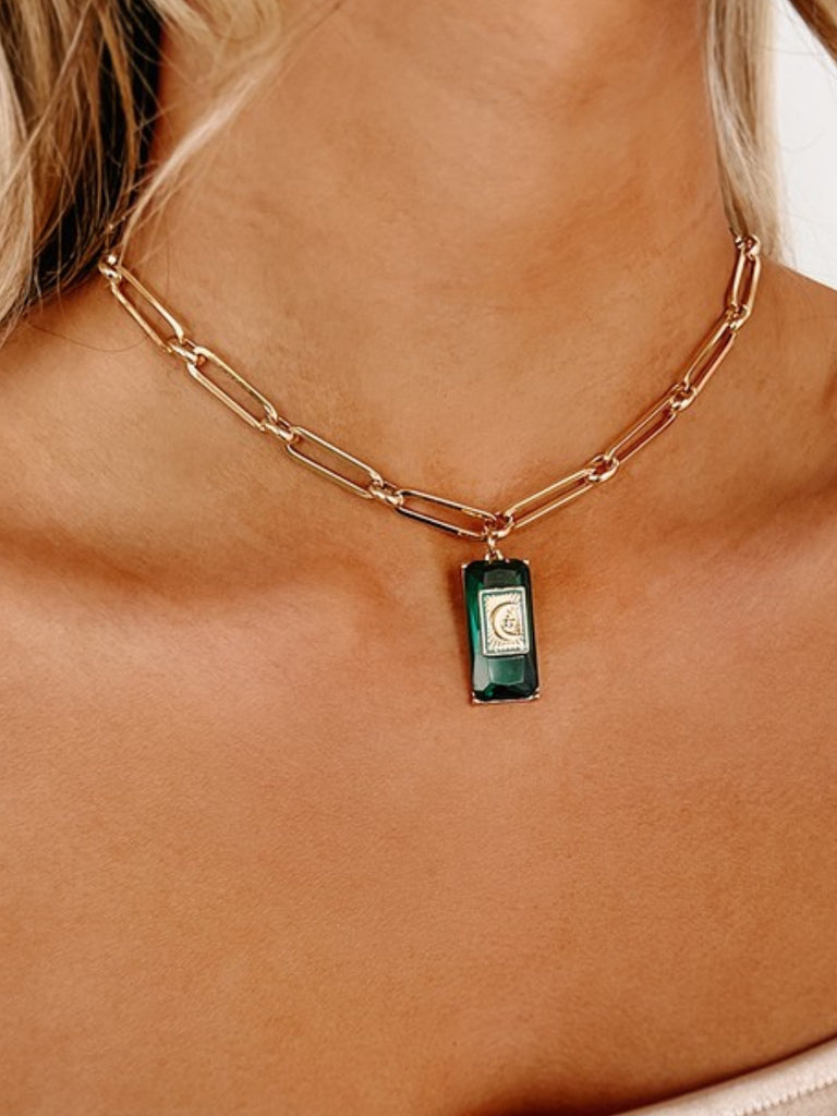 14.5" Gold Necklace, has a moon and star charm, and emerald gem detail with adjustable length and rectangular cable chain.