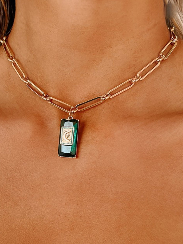 14.5" Gold Necklace, has a moon and star charm, and emerald gem detail with adjustable length and rectangular cable chain.