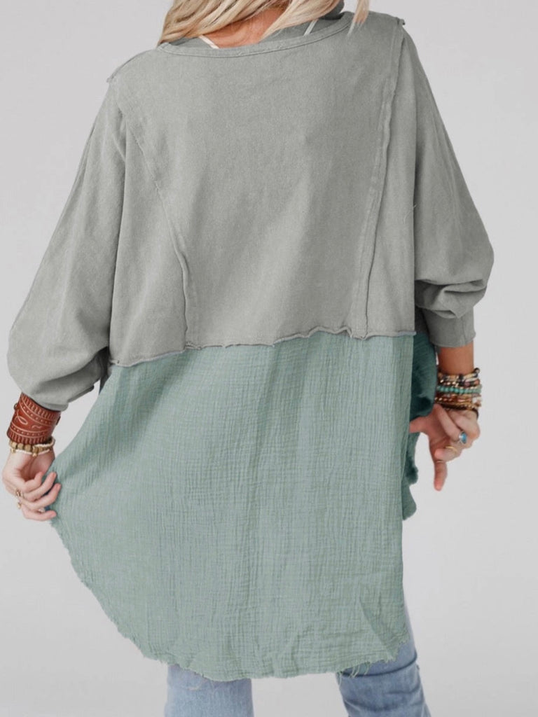 Grey Colour high-low tunic length and split hem pullover, features a round neckline and long sleeves, blend of crinkled gauze and knit, and raw edge design.