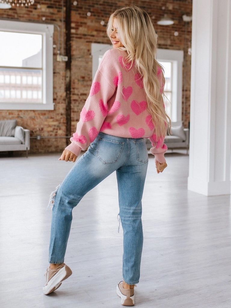 Pink sweater with contrasting fuzzy pink hearts, long sleeved.