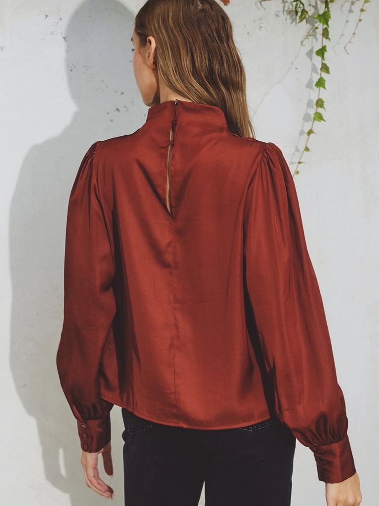 Claret coloured cinch blouse , Features a mock neck, and keyhole closure . Pleating detail on the shoulders and triple buttoned cuffs