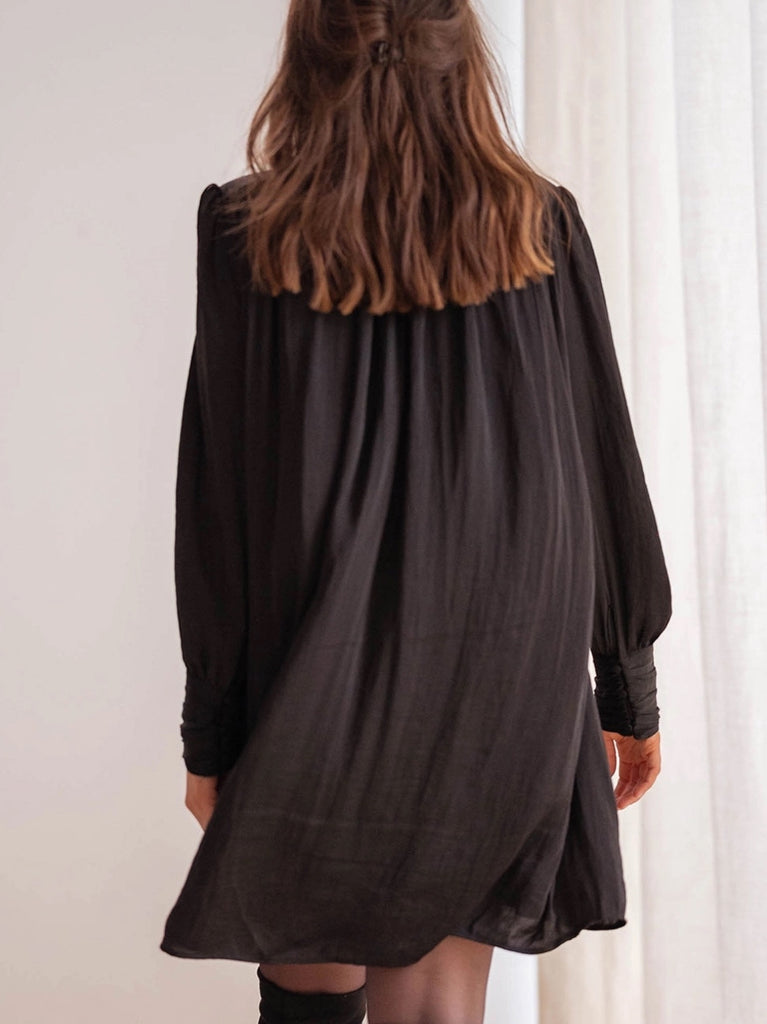 Black pleated mini dress with bishop sleeves.