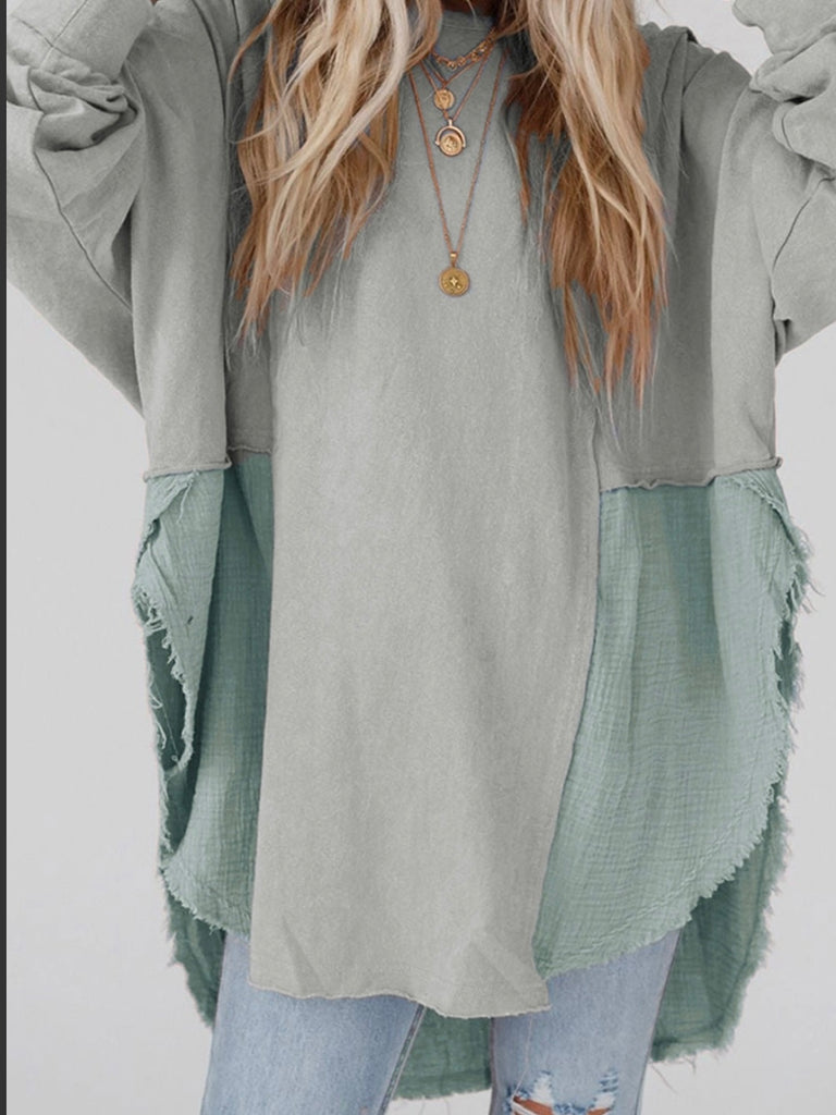 Grey Colour high-low tunic length and split hem pullover, features a round neckline and long sleeves, blend of crinkled gauze and knit, and raw edge design.