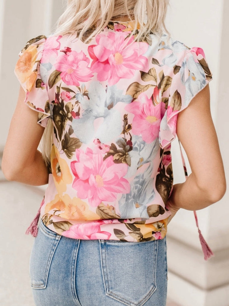 Floral Blouse Blouse features a delicate and feminine floral print, ruffled neckline, and tasseled tie neckline. 