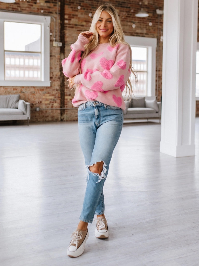 Pink sweater with contrasting fuzzy pink hearts, long sleeved.