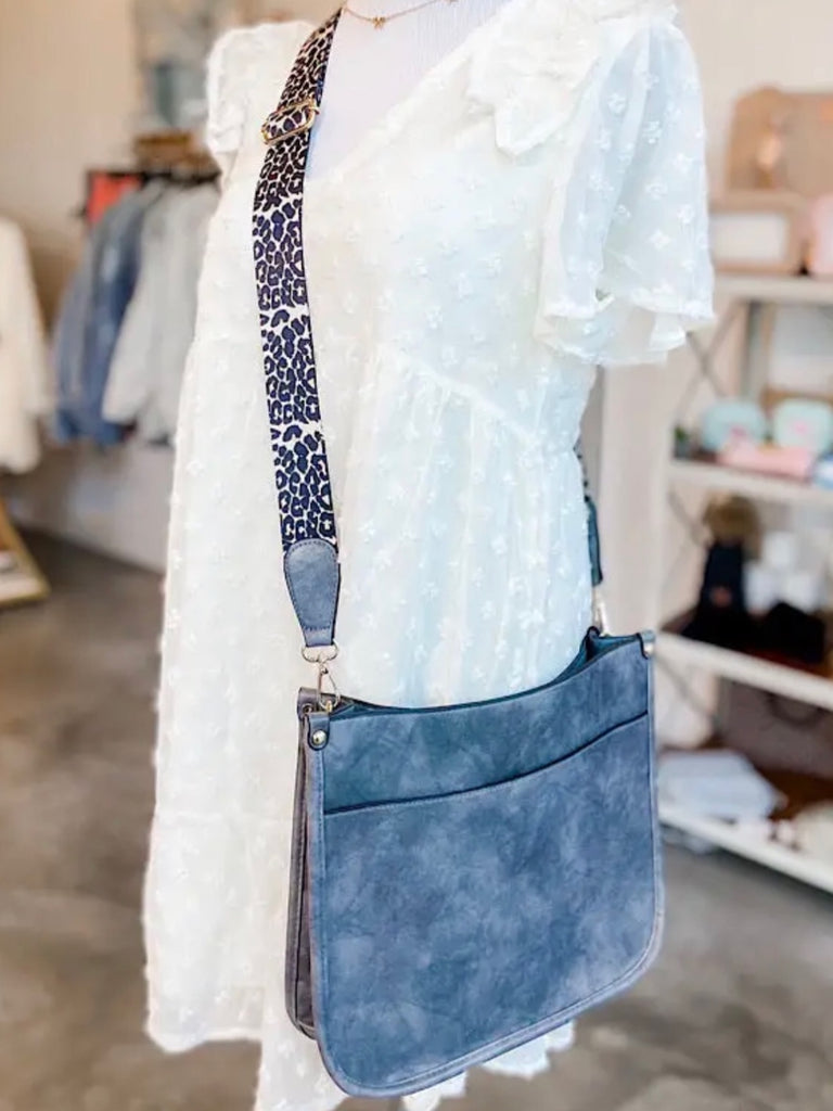 Navy Crossbody bag with leopard print strap. Made with vegan leather, it features a full zipper closure, an exterior back zip pocket, two open slip pockets, and a zipper pocket inside.