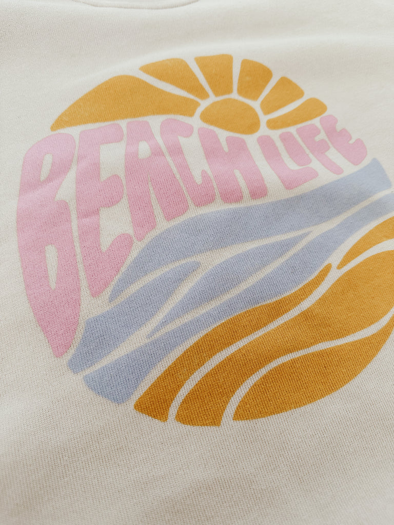 Featuring a soft vintage vibe beach life front graphic sweatshirt in pink, blue, and yellow ocean colours.