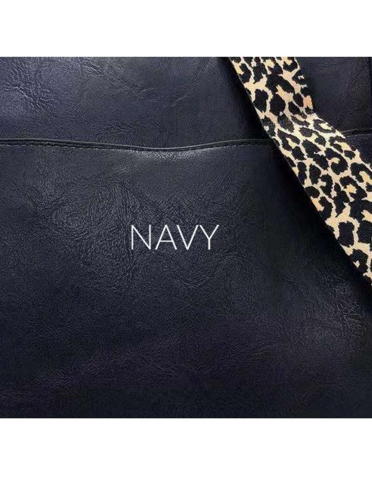 Navy  Crossbody bag with leopard print strap. Made with vegan leather, it features a full zipper closure, an exterior back zip pocket, two open slip pockets, and a zipper pocket inside.