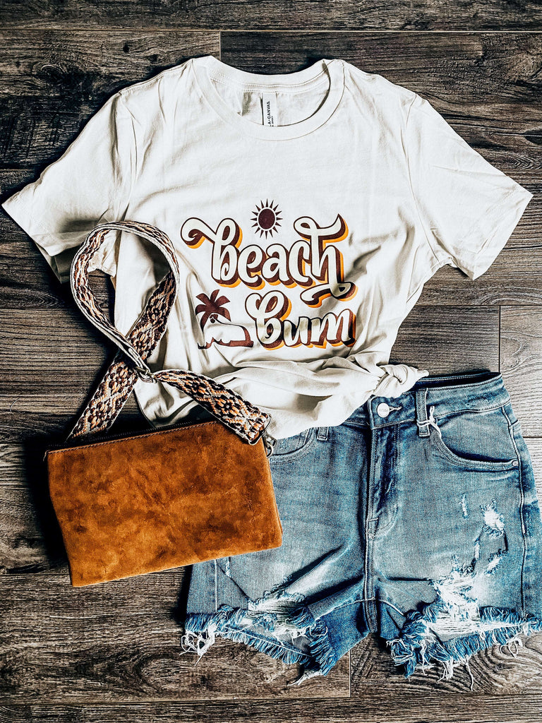    Beach Bum Tee is a soft cream colour with a yellow and tan colour front graphic 