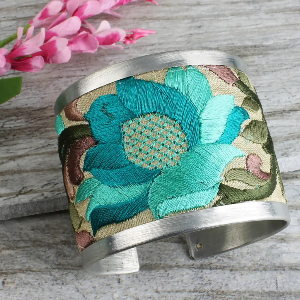 2" Wide Brushed Silver Cuff with bold cream coloured fabric embroidered with turquoise and purple floral designs.